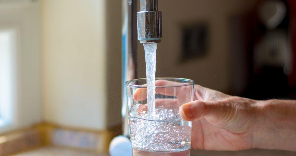person filling up glass of water